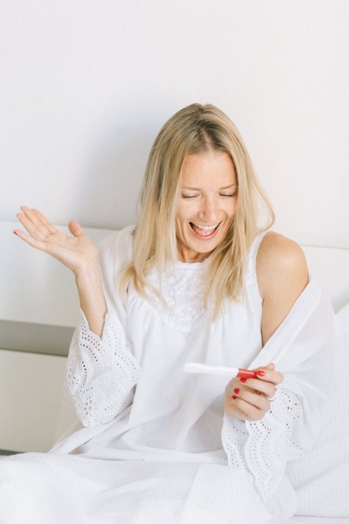 pexels photo 5982081 Happy woman rejoicing over a positive pregnancy test result indoors.