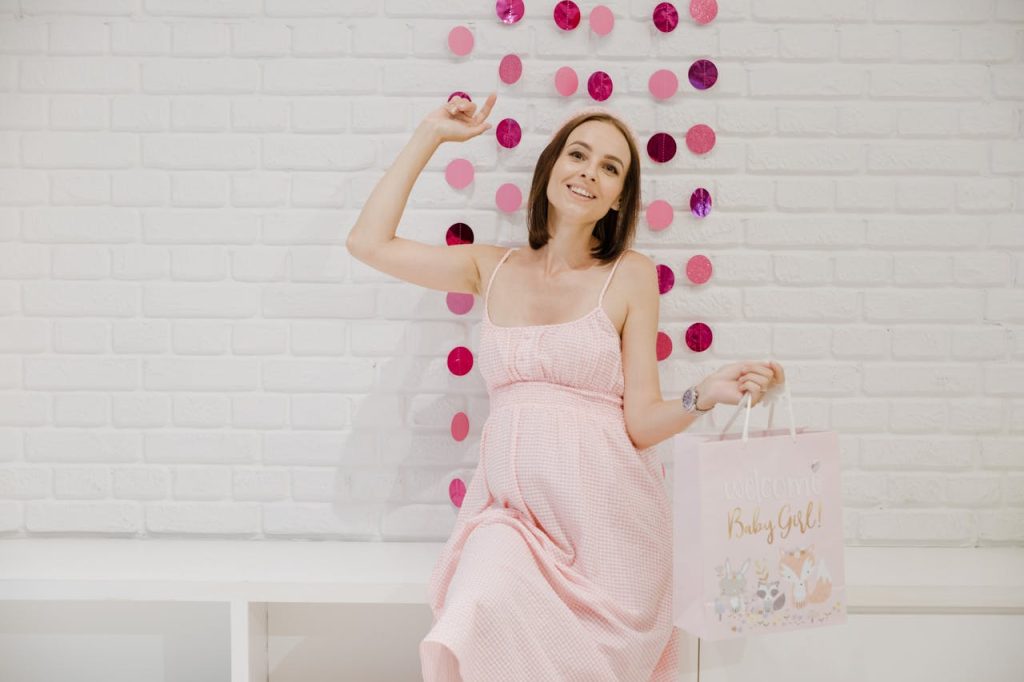 Smiling pregnant woman in pink enjoying baby shower indoors.