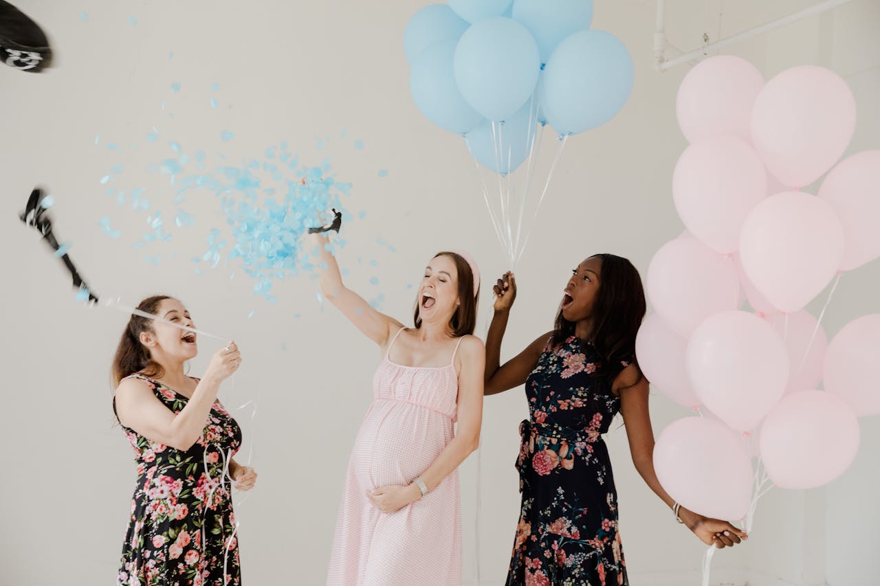Three women celebrate a baby shower with balloons and confetti, radiating happiness and togetherness.